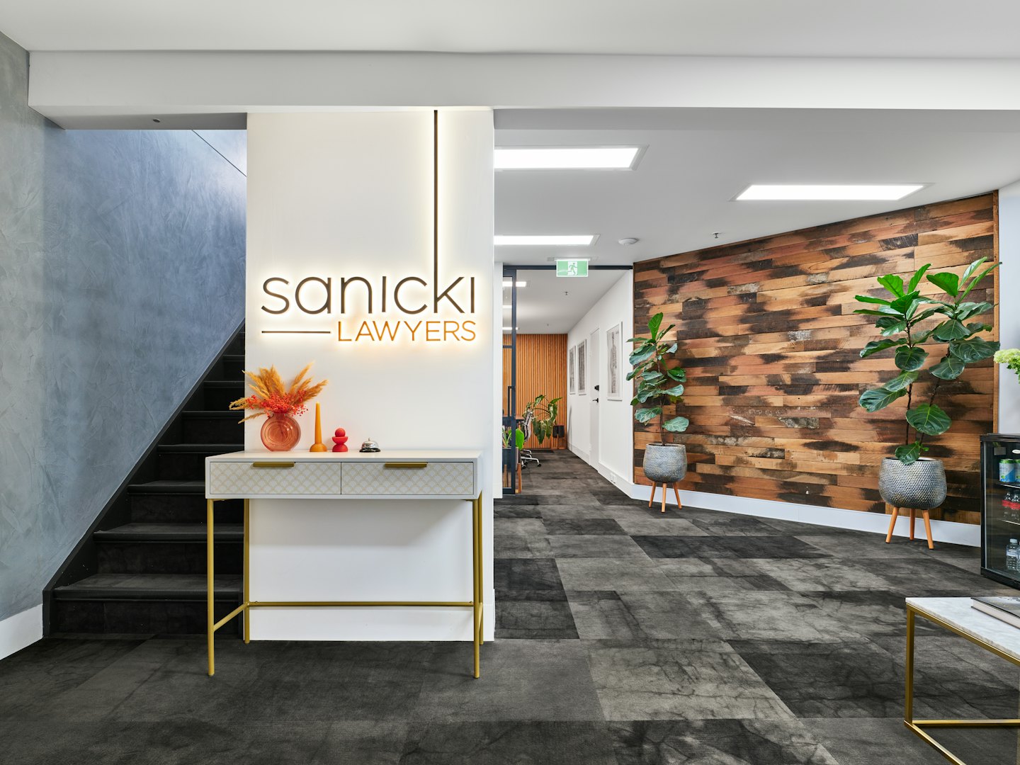 Area reception moderna con logo Sanicki Lawyers su parete.